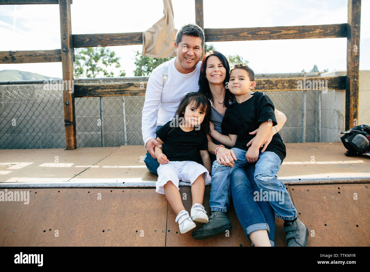 Famiglia di quattro persone si siede sul mezzo tubo mentre sorridente per la fotocamera Foto Stock