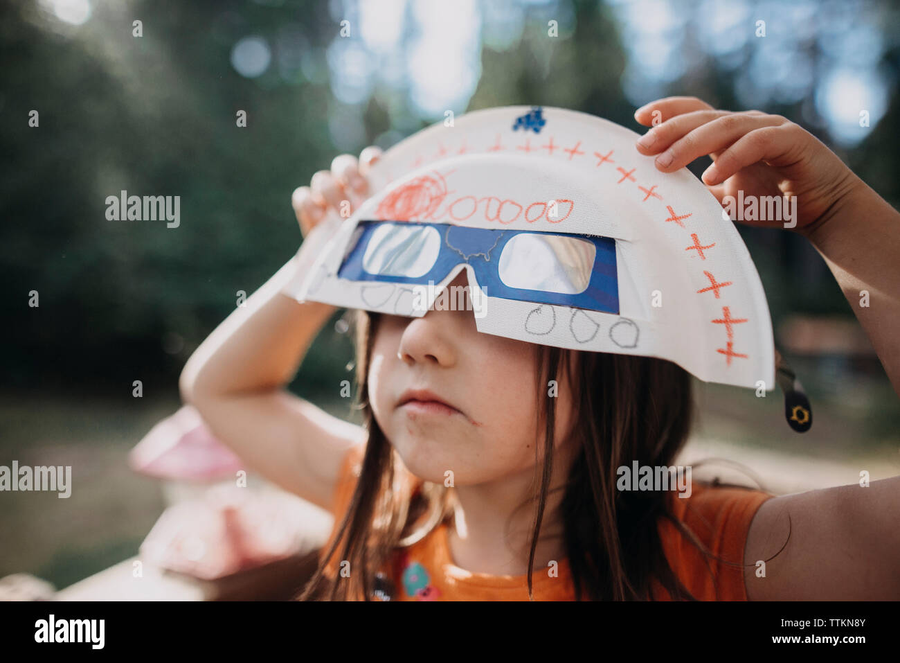 Ragazza con eclissi solare gli occhiali e la maschera durante il gioco in posizione di parcheggio Foto Stock