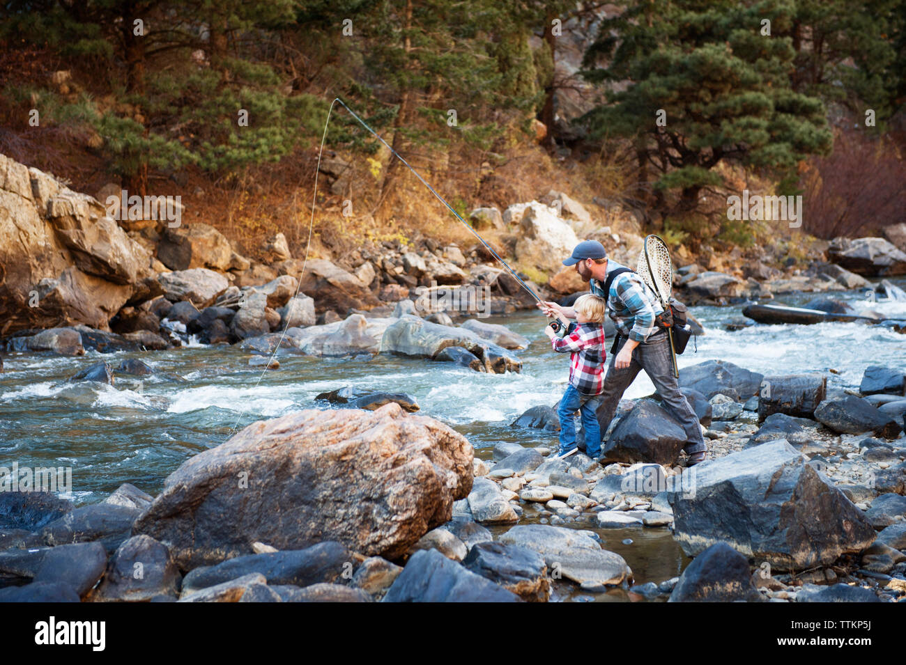 Padre e figlio la pesca in fiume contro la foresta Foto Stock