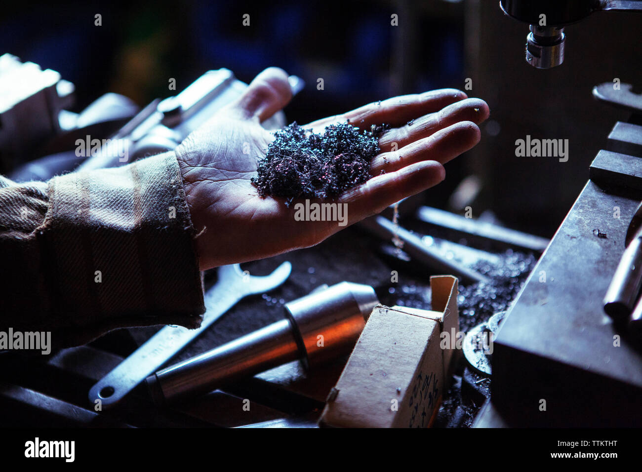 Immagine ritagliata di lavoratore tenendo la presenza di limatura di ferro nel workshop Foto Stock