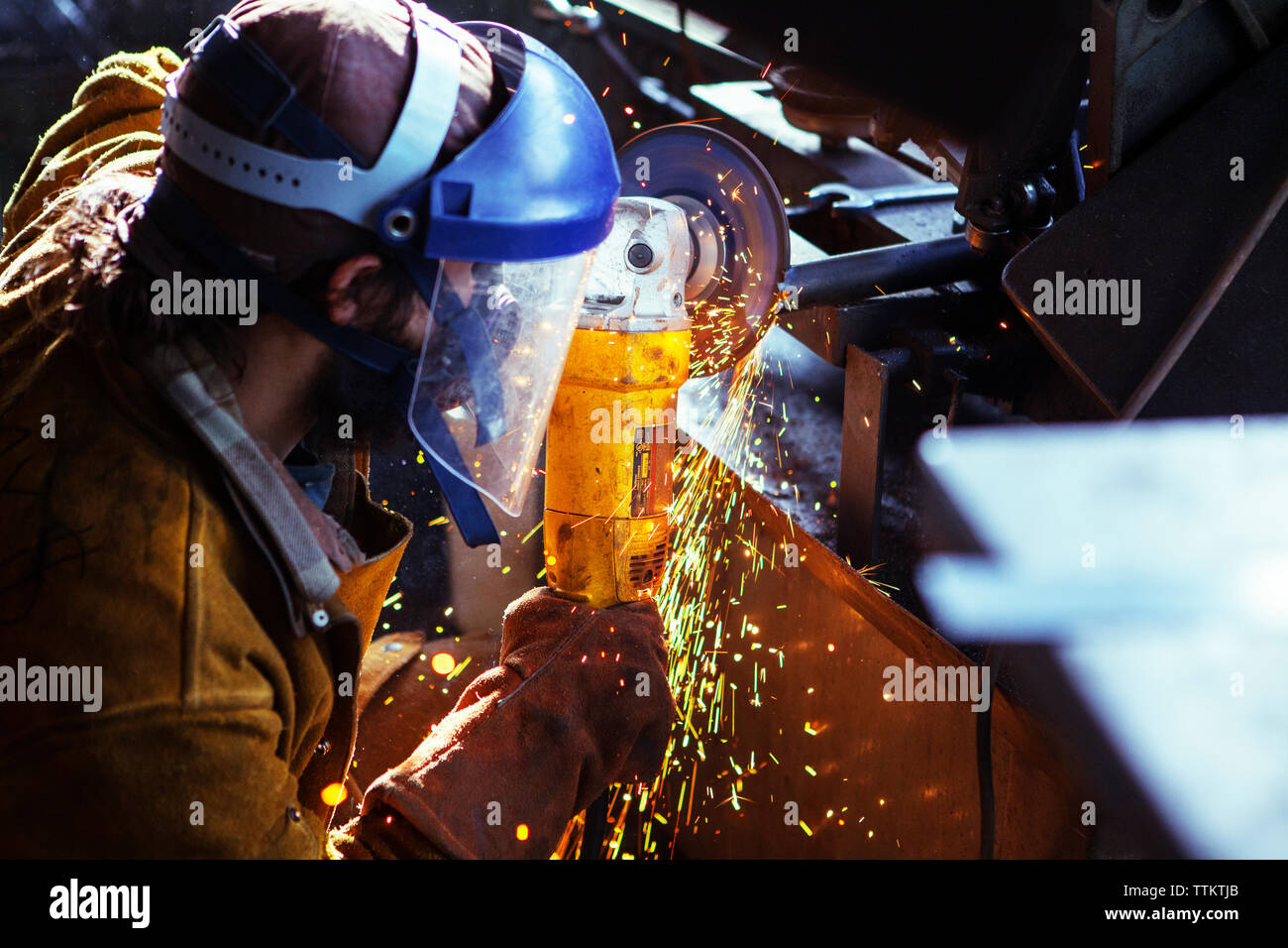 lavoratore che taglia l'asta in ferro con sega elettrica in fabbrica Foto Stock