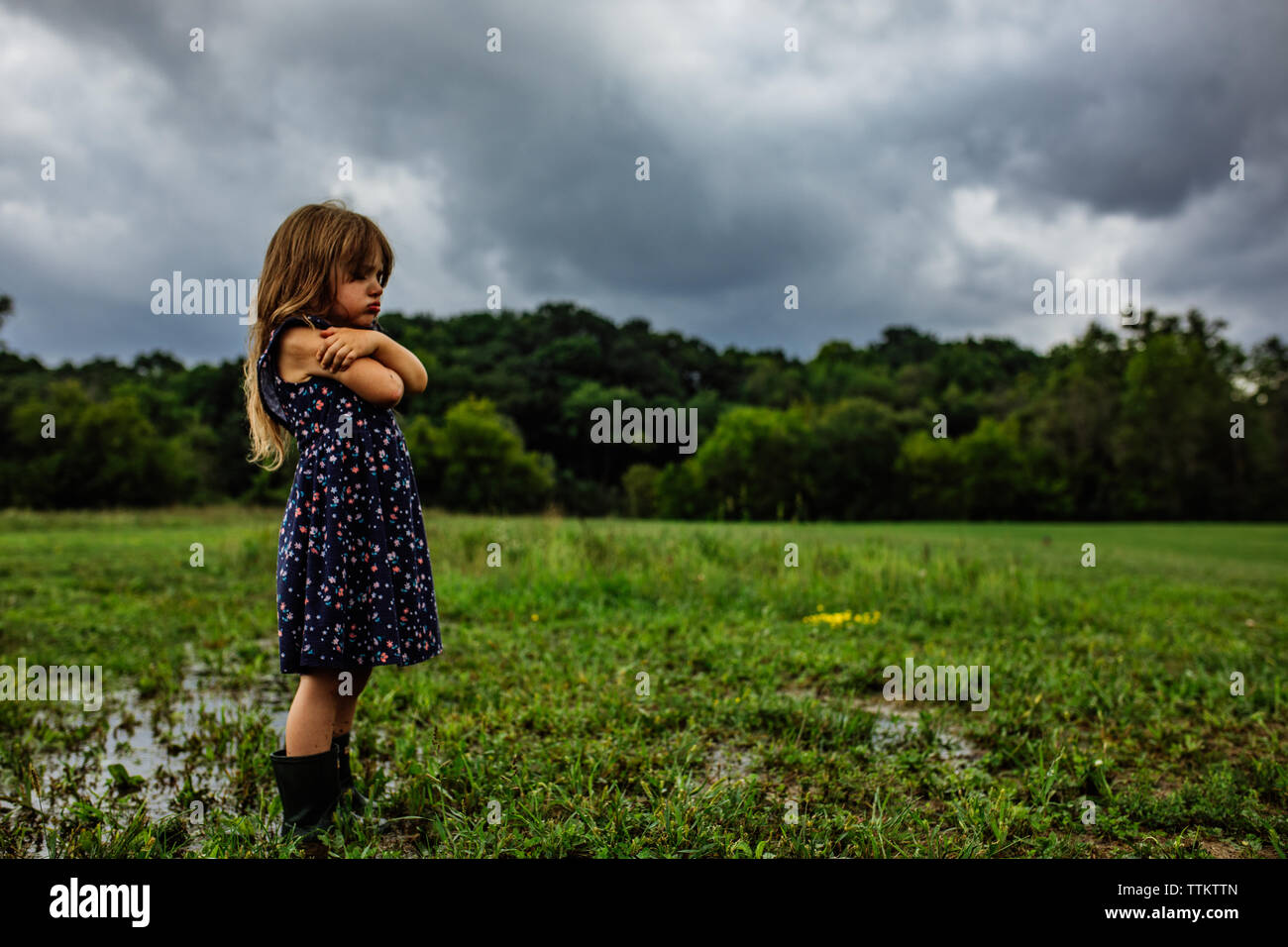 Arrabbiato bambino bagnato in un giorno di pioggia in un campo umido gettando un tantrum Foto Stock
