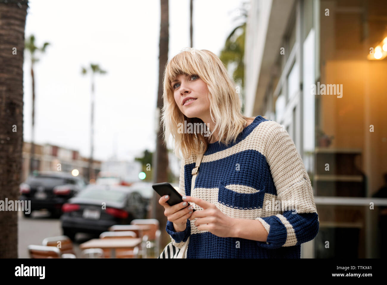 Premurosa donna azienda smart phone dalla strada di città Foto Stock