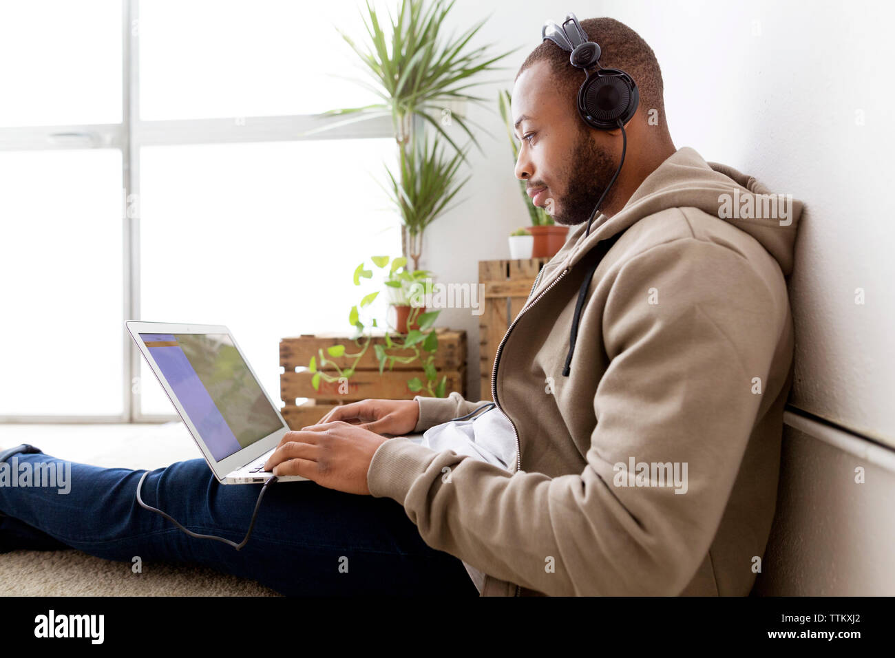 Vista laterale di imprenditore creativo ascoltare musica mentre utilizzando computer portatile in ufficio Foto Stock