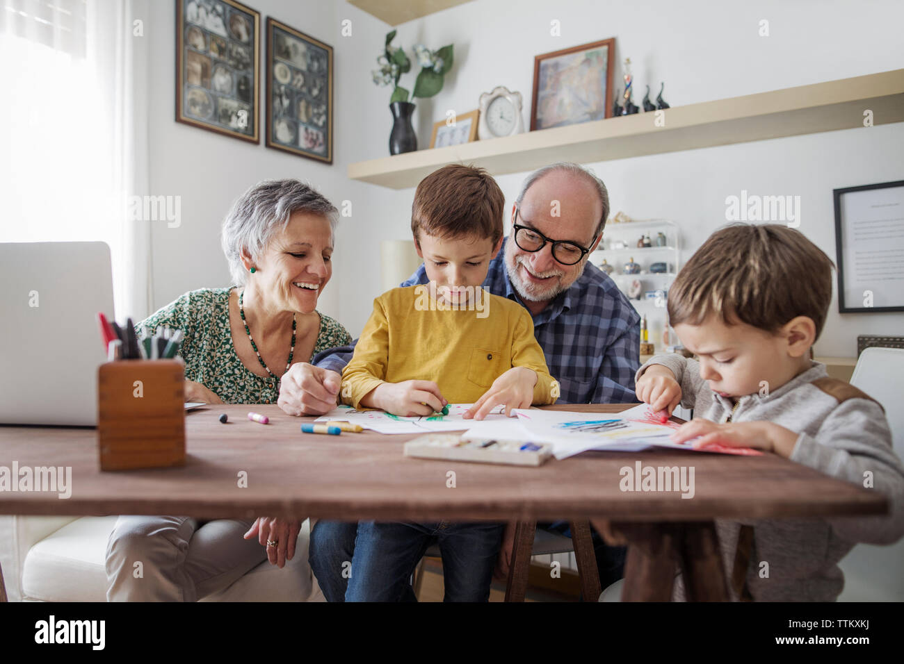 Nonni felici guardando nipoti facendo disegni a casa Foto Stock