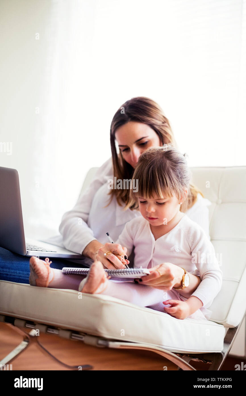 La madre ad assistere la figlia a studiare a casa Foto Stock