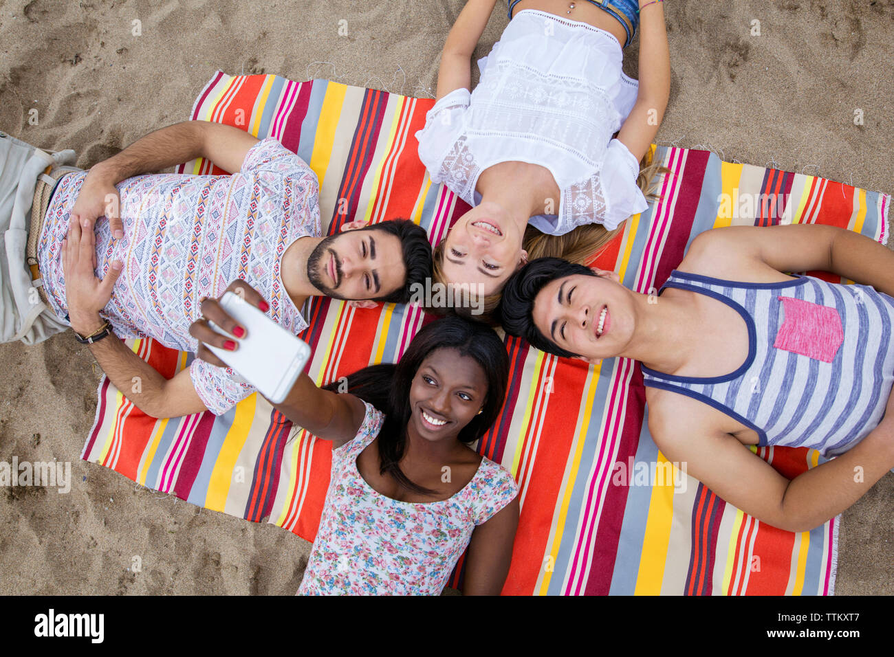 Vista aerea del multi-etnico amici prendendo selfie sdraiati su huddle sulla spiaggia Foto Stock