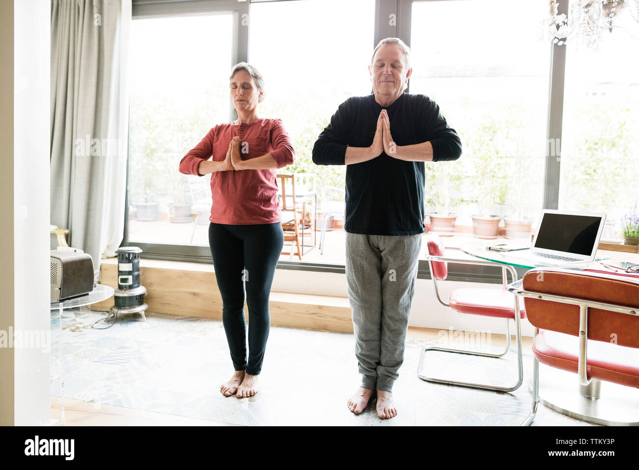 Rilassata coppia senior a praticare yoga a casa Foto Stock