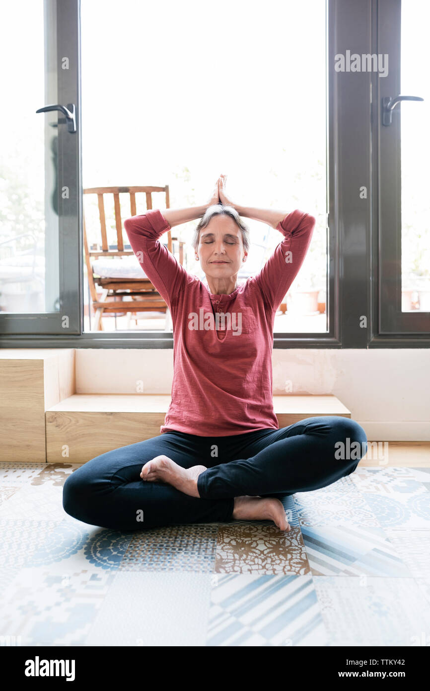 Donna matura fare yoga a casa Foto Stock