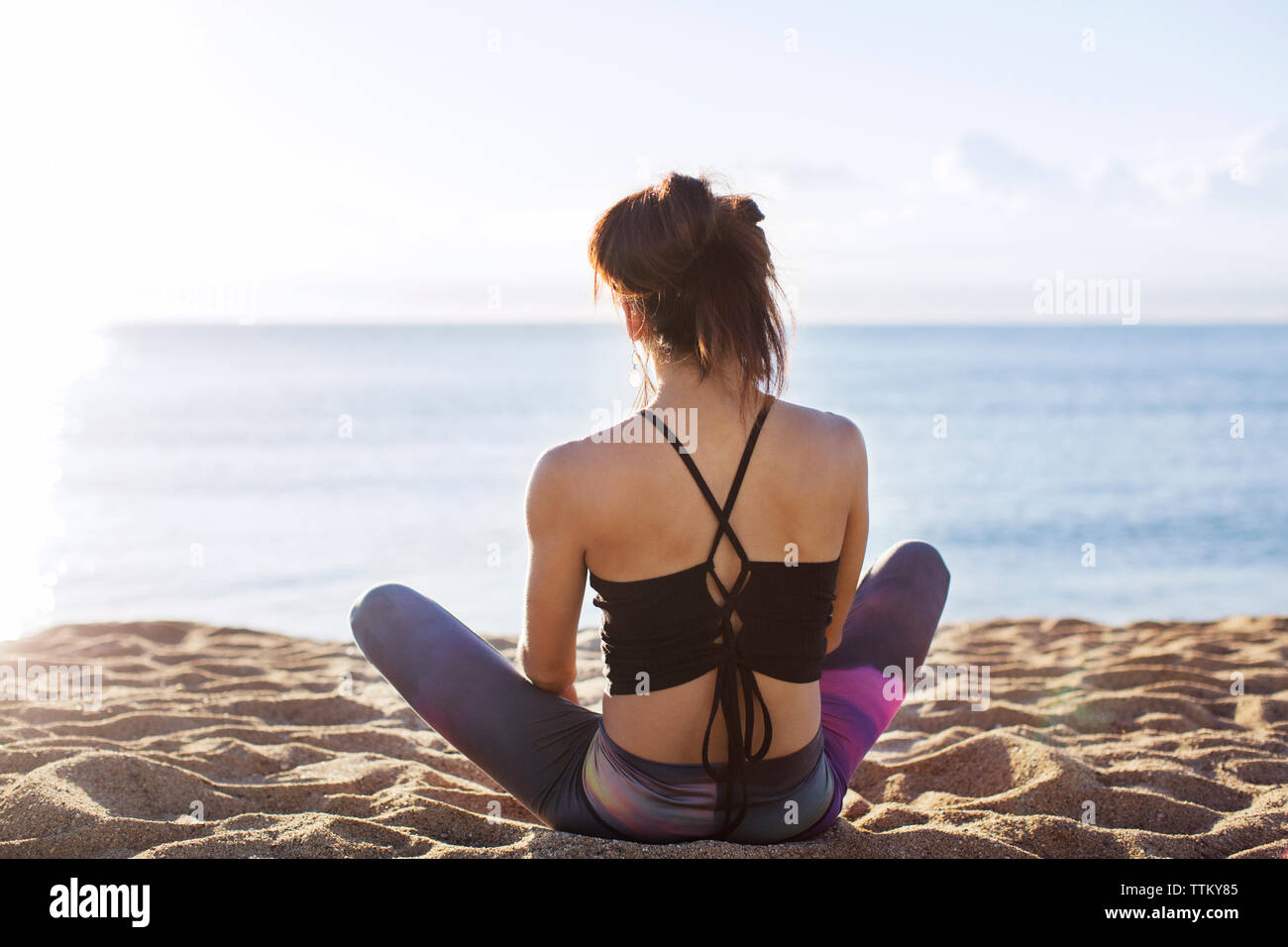Vista posteriore della donna fare yoga in riva al mare Foto Stock