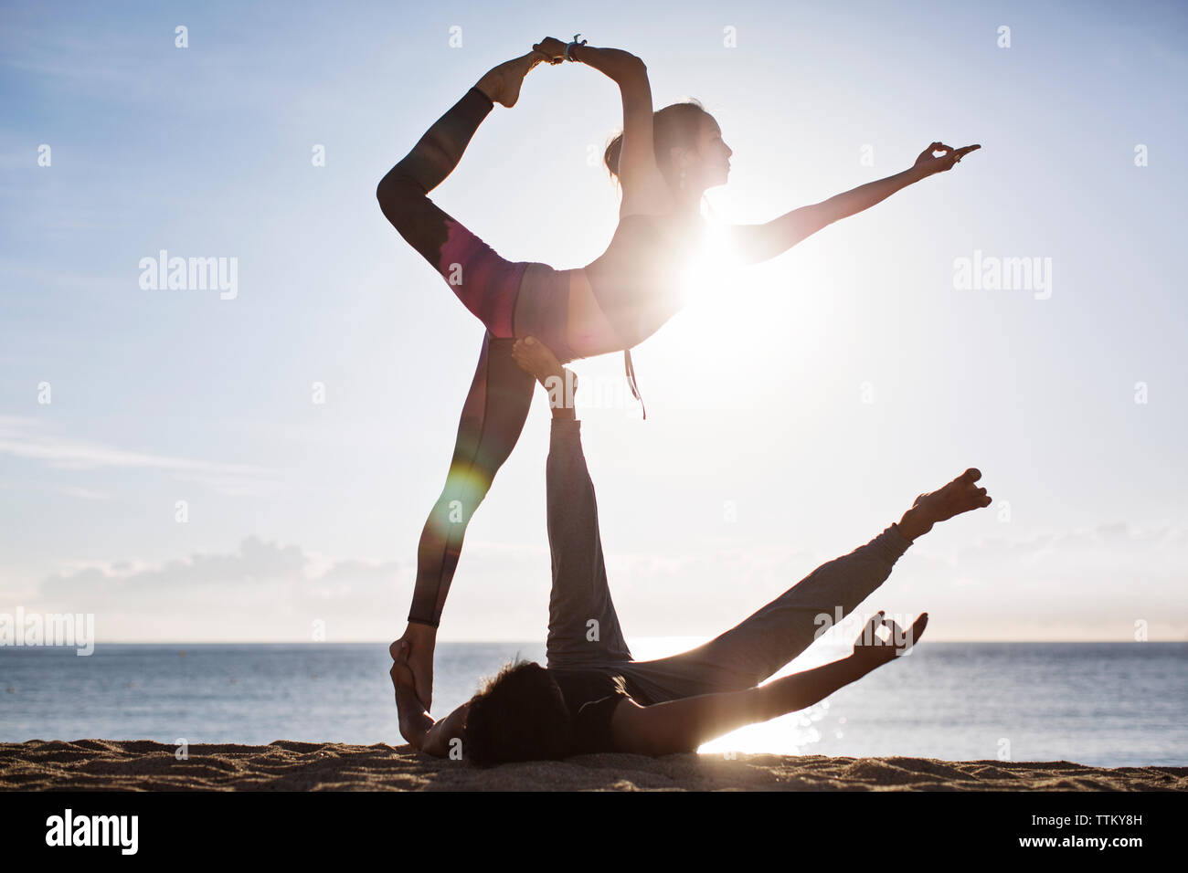 Giovane fare yoga sulla spiaggia contro sky durante l'estate Foto Stock