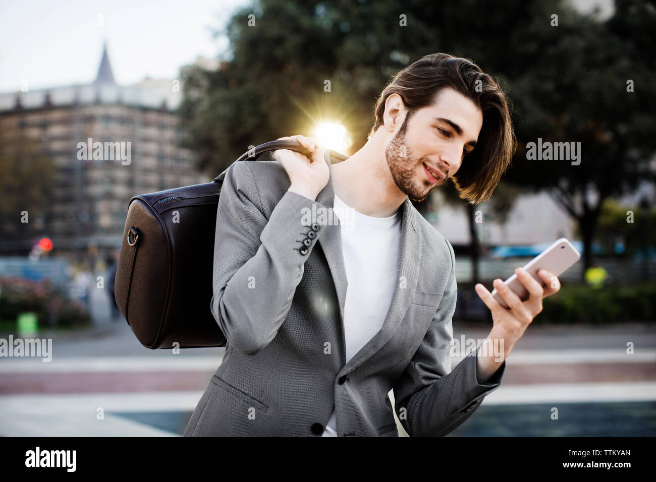 borsa da viaggio per uomo d'affari mentre utilizza il telefono cellulare Foto Stock