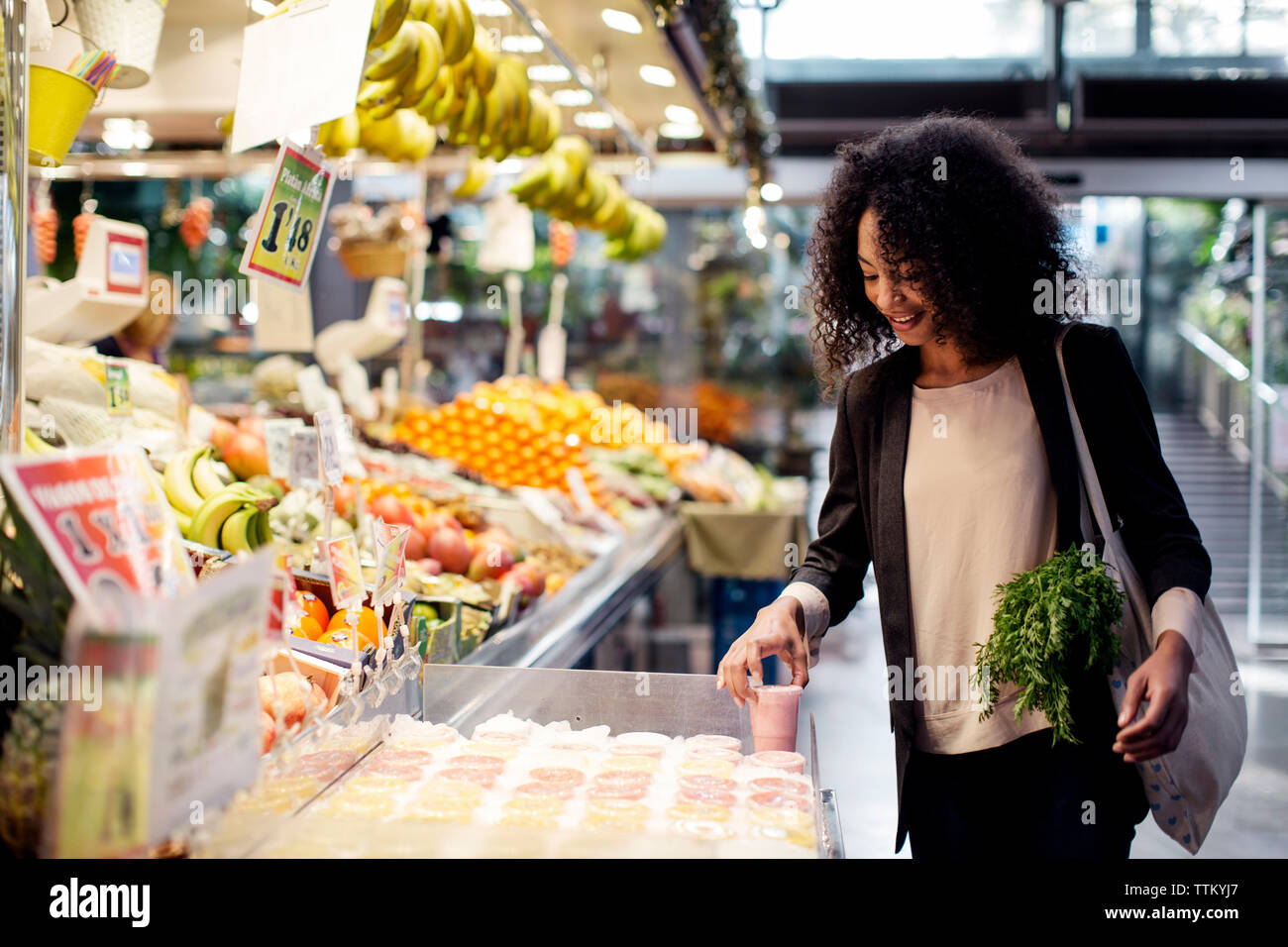 Donna succo di acquisto mentre si sta in piedi in negozio Foto Stock