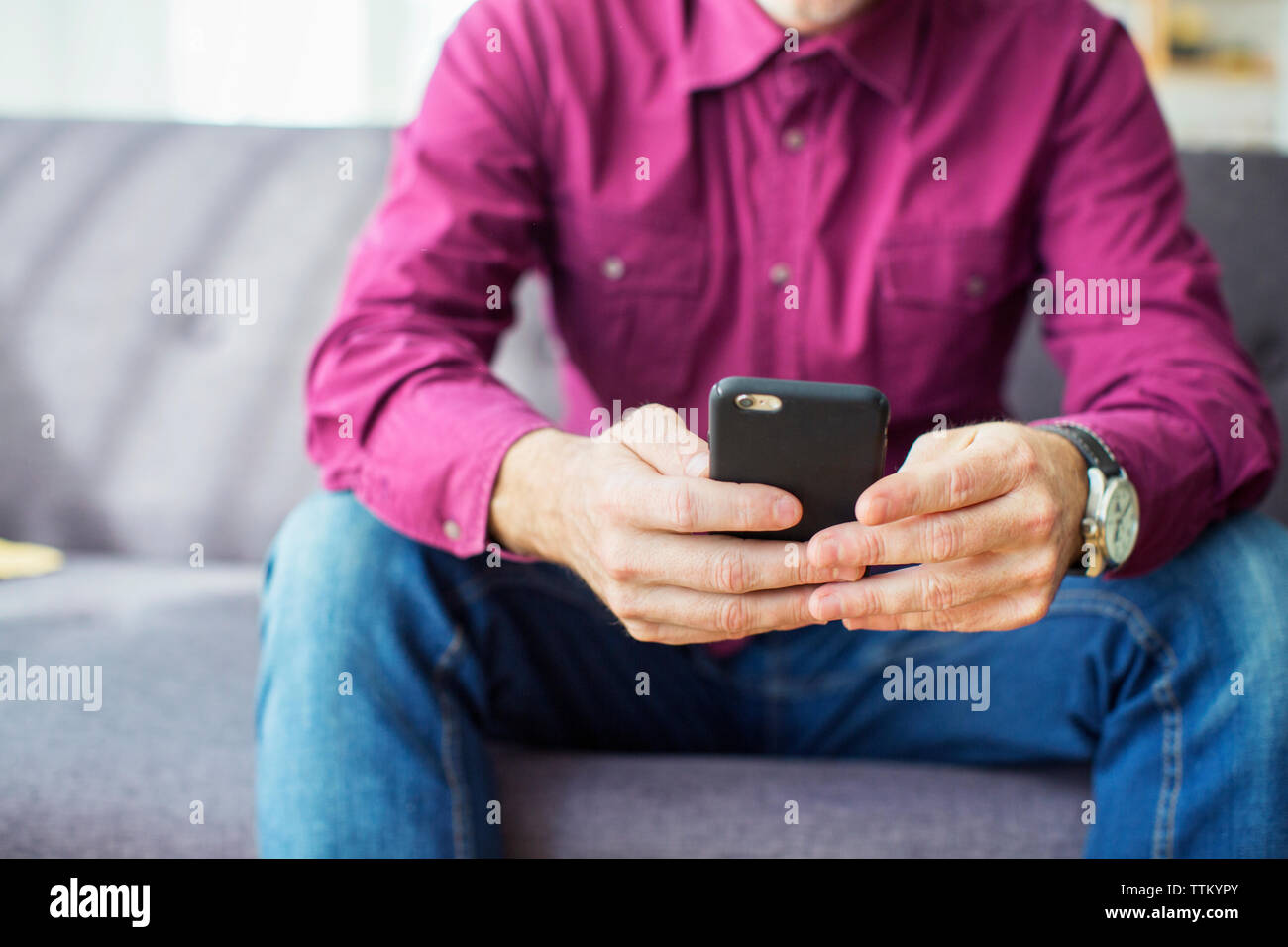 Sezione mediana di imprenditore utilizzando il telefono cellulare sul divano in office Foto Stock
