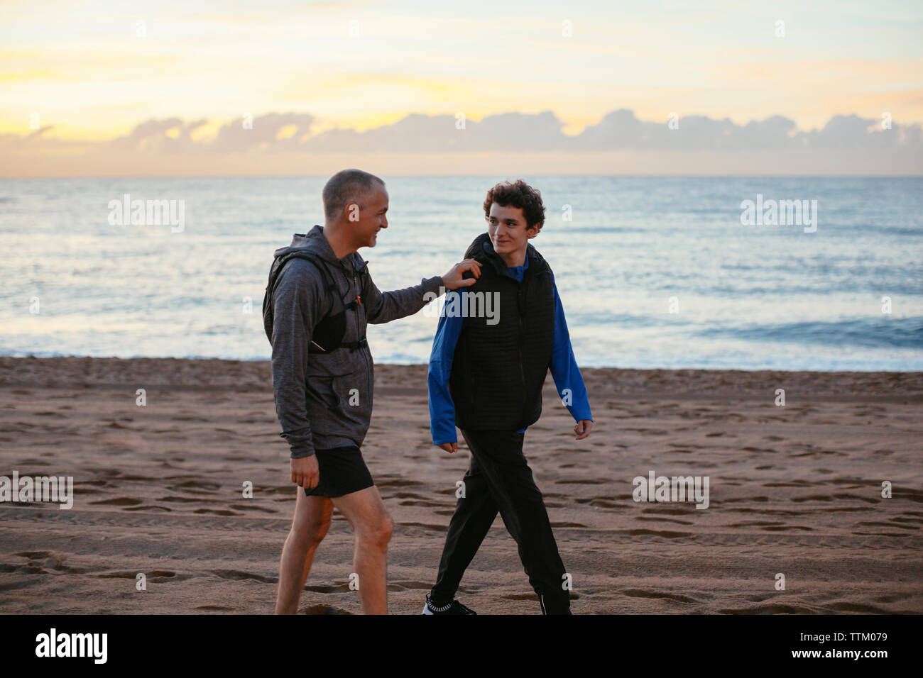 Felice di padre e figlio a piedi di spiaggia contro sky Foto Stock