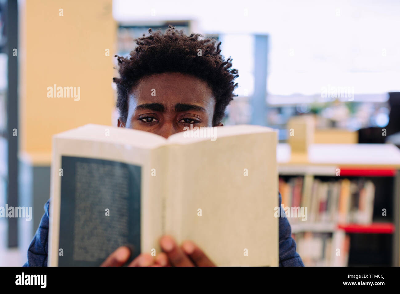 Uomo libro lettura mentre è seduto nella libreria Foto Stock