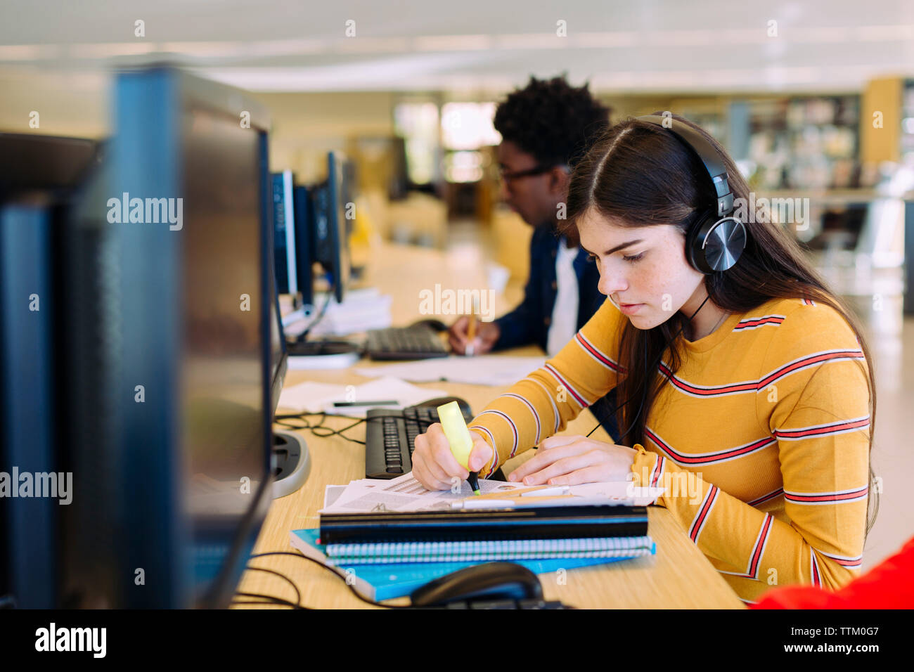 Gli studenti utilizzano i computer desktop mentre è seduto nella libreria Foto Stock