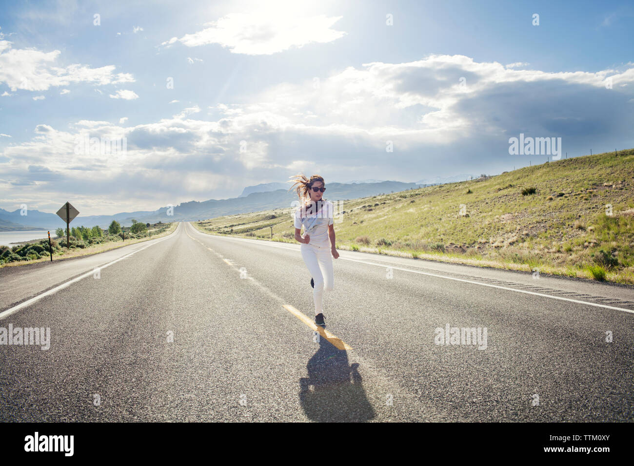 Vista frontale della donna in esecuzione in strada contro sky sulla giornata di sole Foto Stock