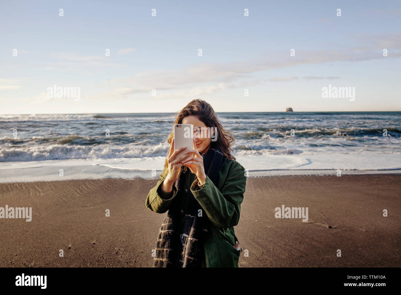 Bella donna fotografando attraverso smart phone beach Foto Stock