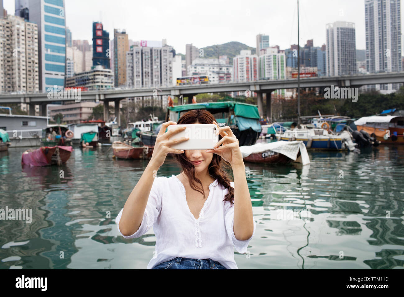 Turista femminile fotografare in porto in città Foto Stock