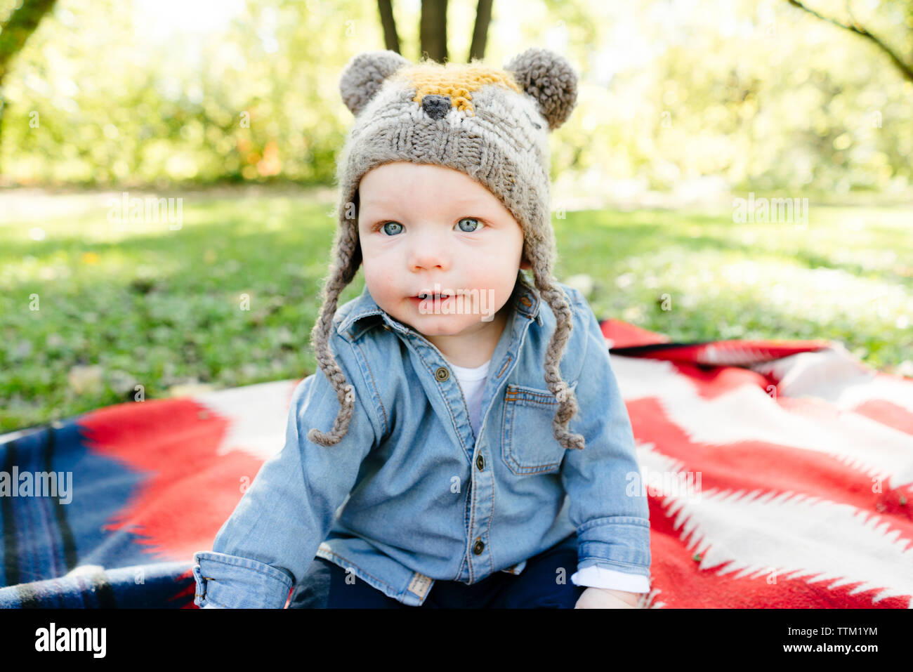 Un bambino in un cappello si siede su una coperta al di fuori Foto Stock