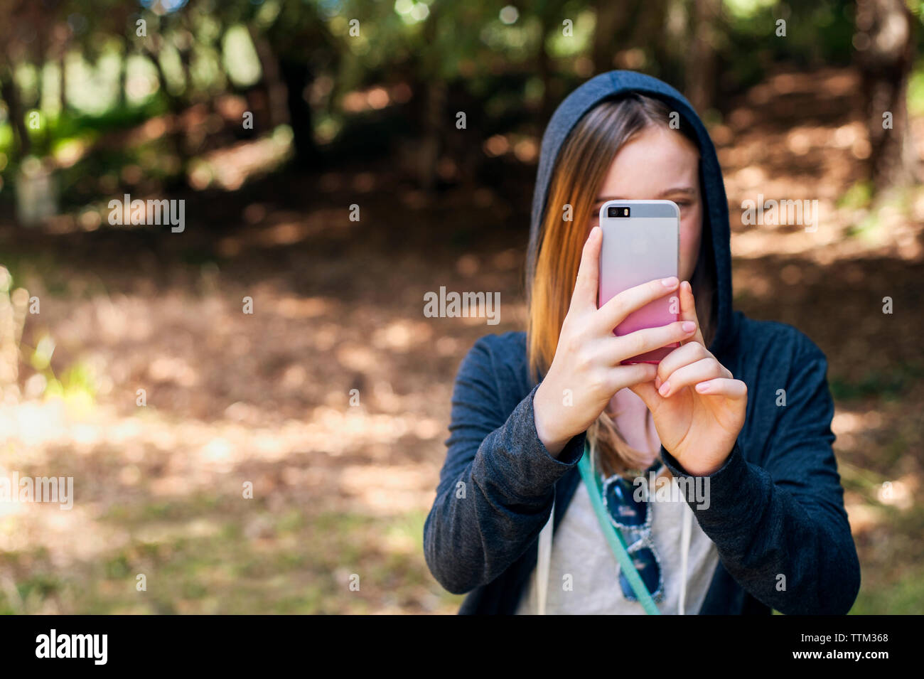 Ragazza adolescente fotografando attraverso smart phone in posizione di parcheggio Foto Stock