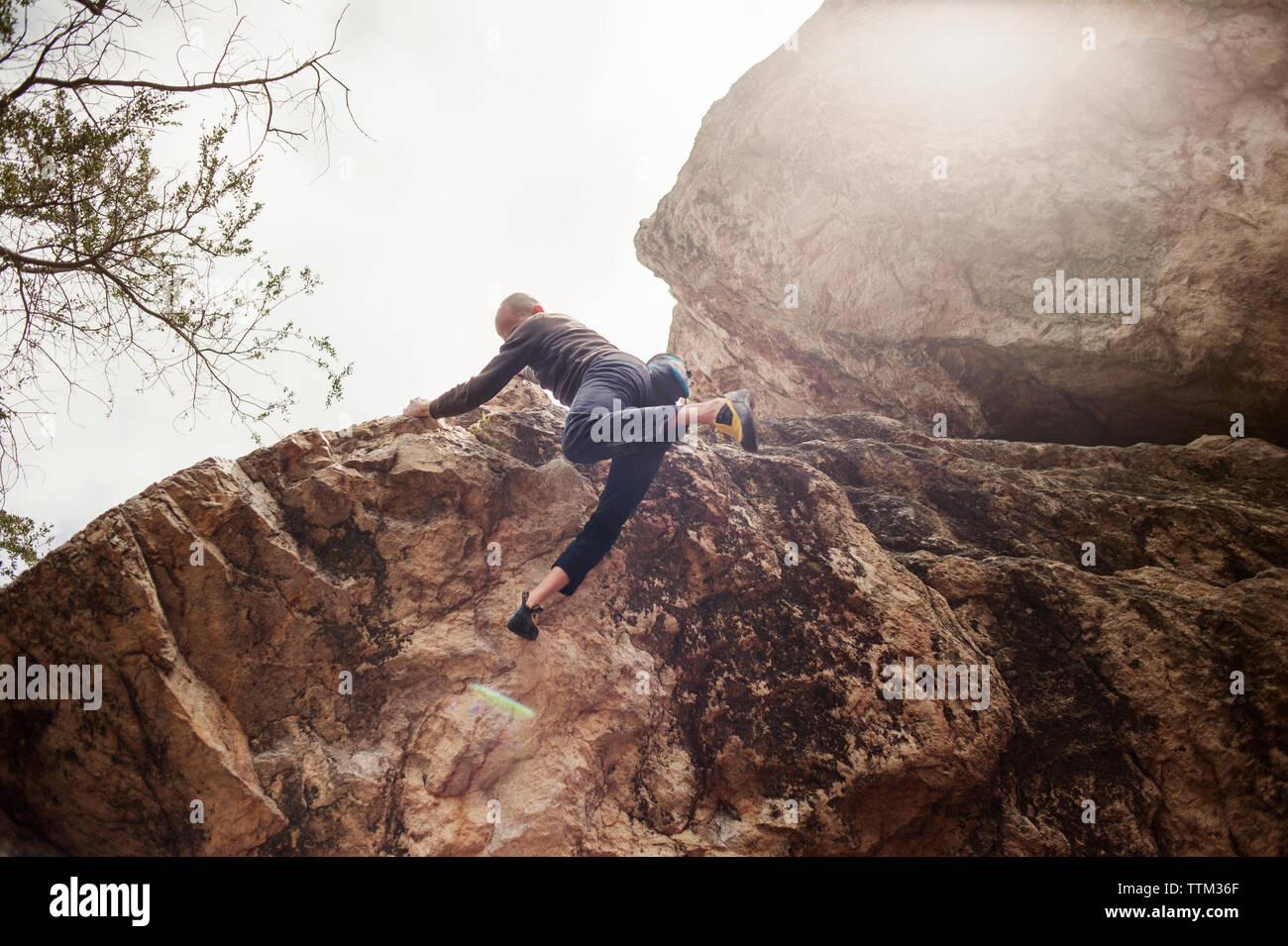 Basso angolo di visione dell uomo che salta da roccia sulla giornata di sole Foto Stock
