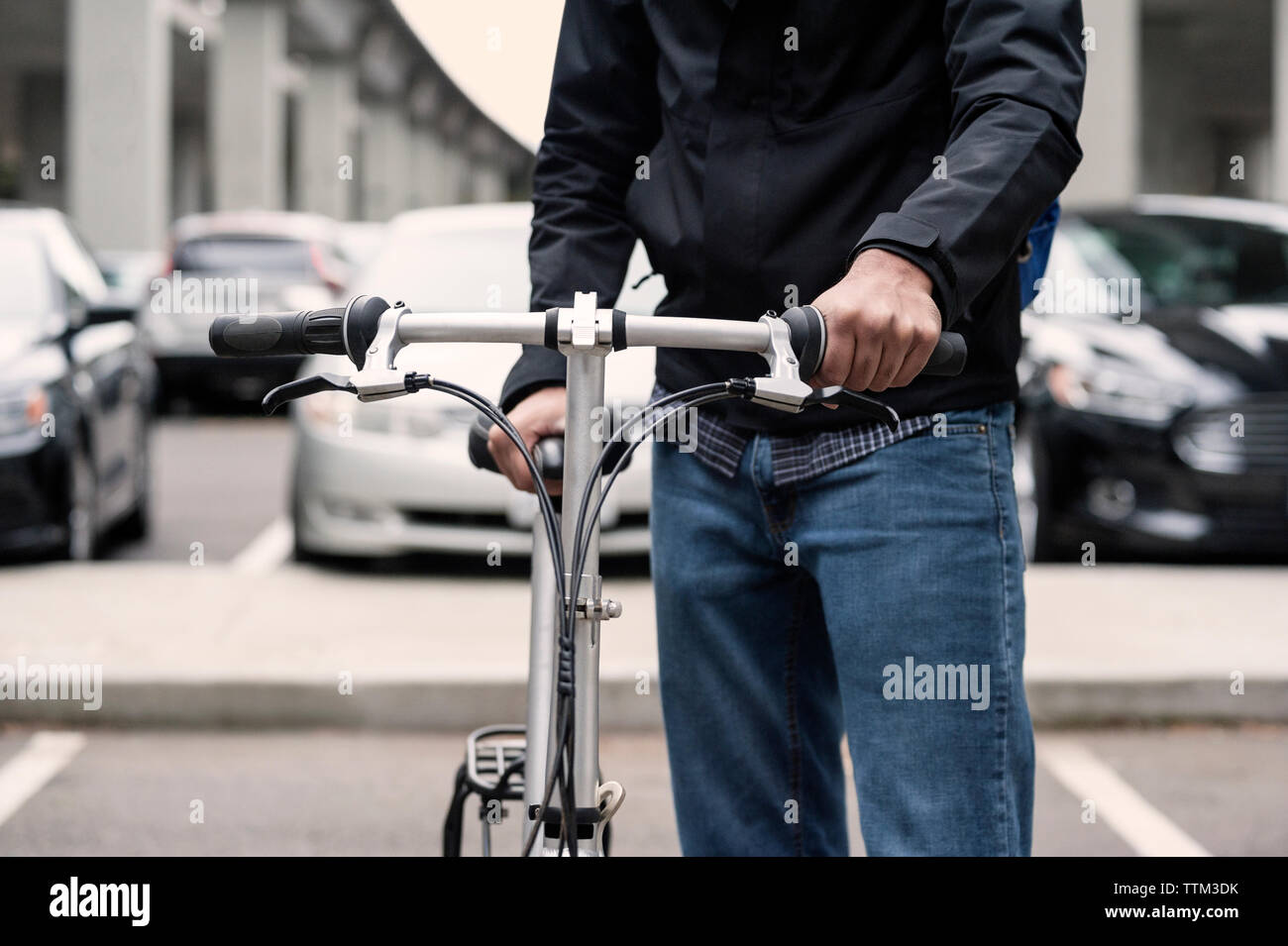 Sezione mediana di imprenditore tenendo bicicletta su una strada di città Foto Stock