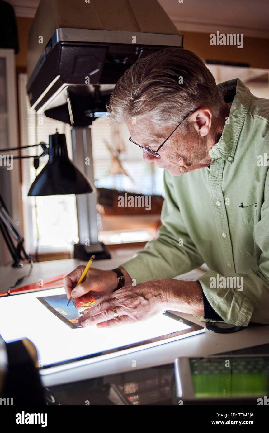 Senior uomo disegno sulla tavoletta grafica a casa Foto Stock