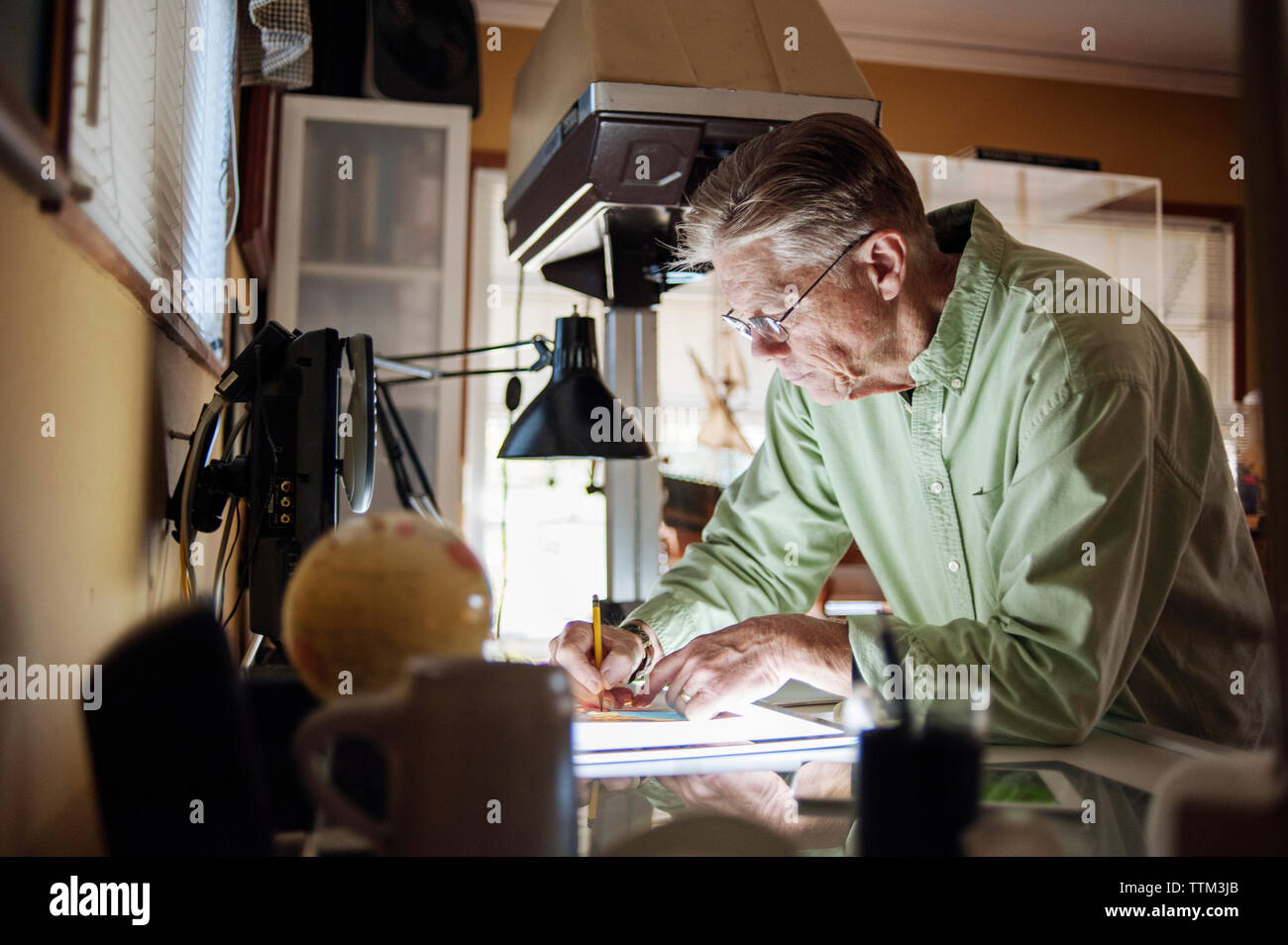 Senior uomo al lavoro su tavoletta grafica a casa Foto Stock