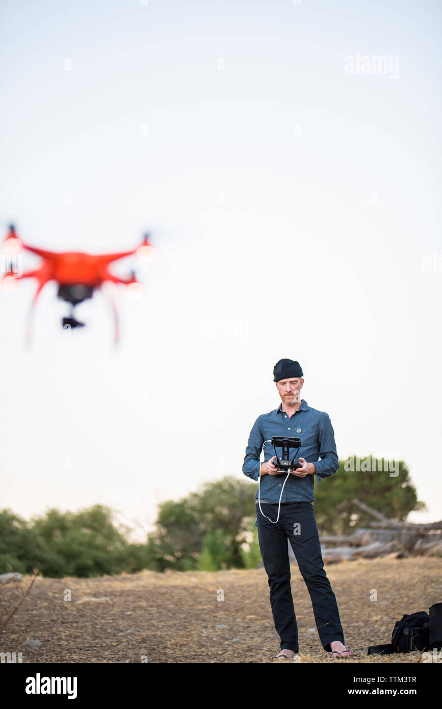 Lunghezza completa di uomo drone di funzionamento tramite telecomando contro il cielo chiaro Foto Stock