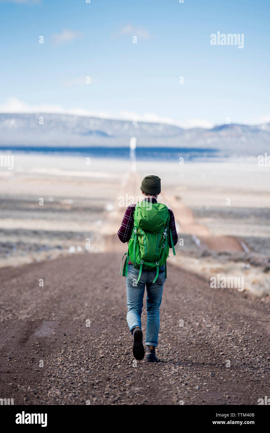 Vista posteriore di un escursionista con zaino verde a piedi di deserto Foto Stock