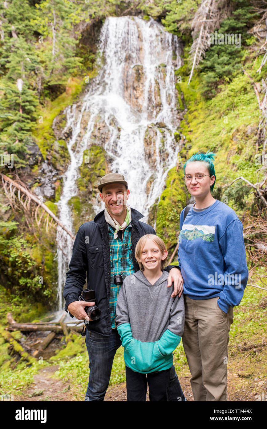 Ritratto di famiglia felice in piedi contro la cascata nel Parco Nazionale di Olympic Foto Stock