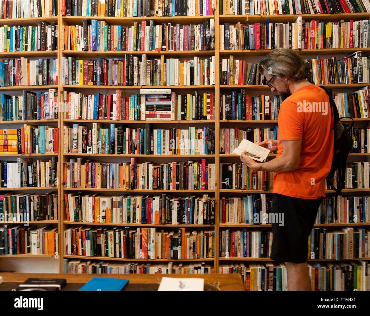 Uomo libro di lettura all'interno di St Georges usati a bookshop in Prenzlauer Berg di Berlino, Germania Foto Stock