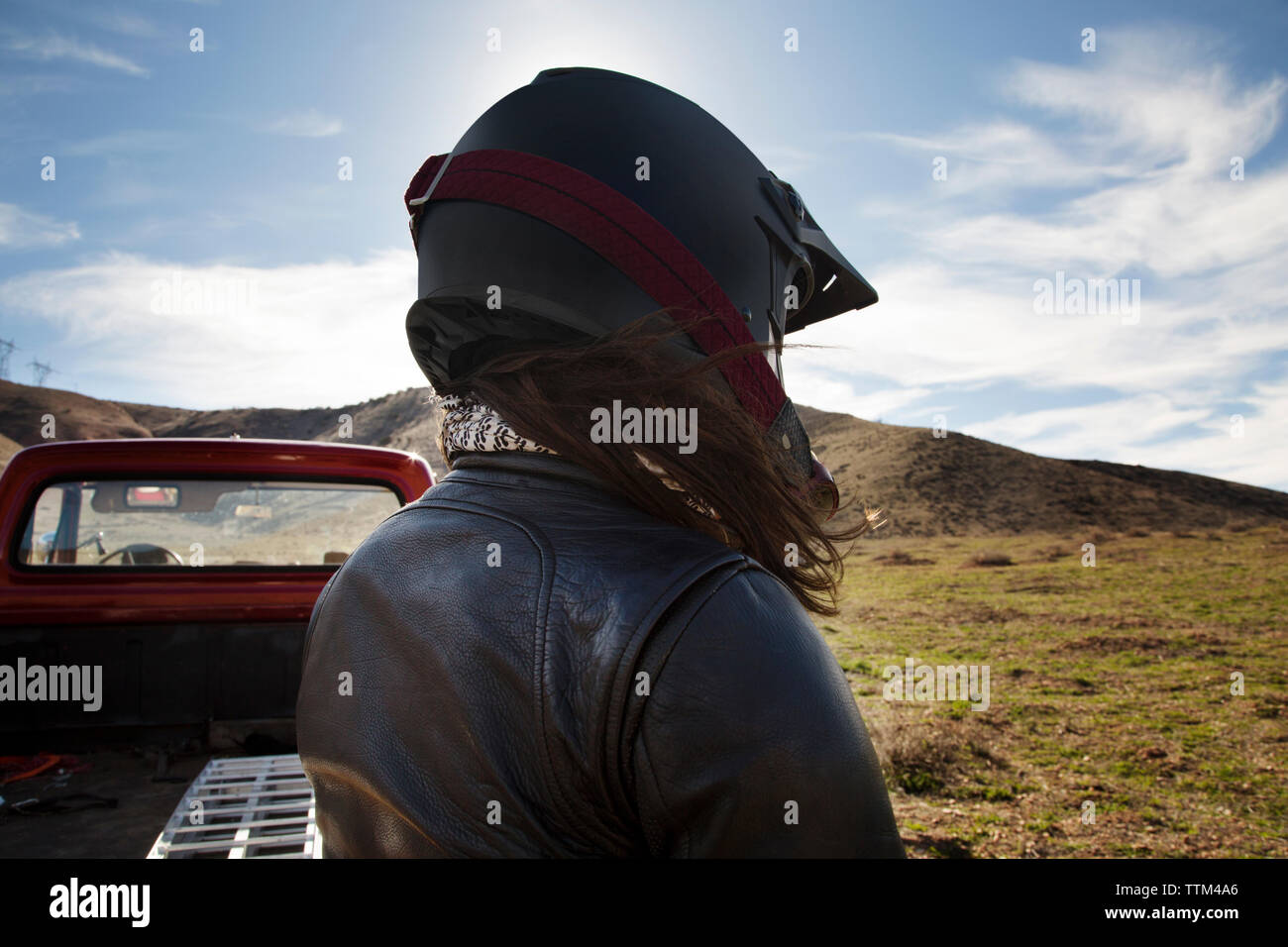 Vista posteriore del biker femmina indossando il casco da pick-up truck sulla montagna contro sky Foto Stock