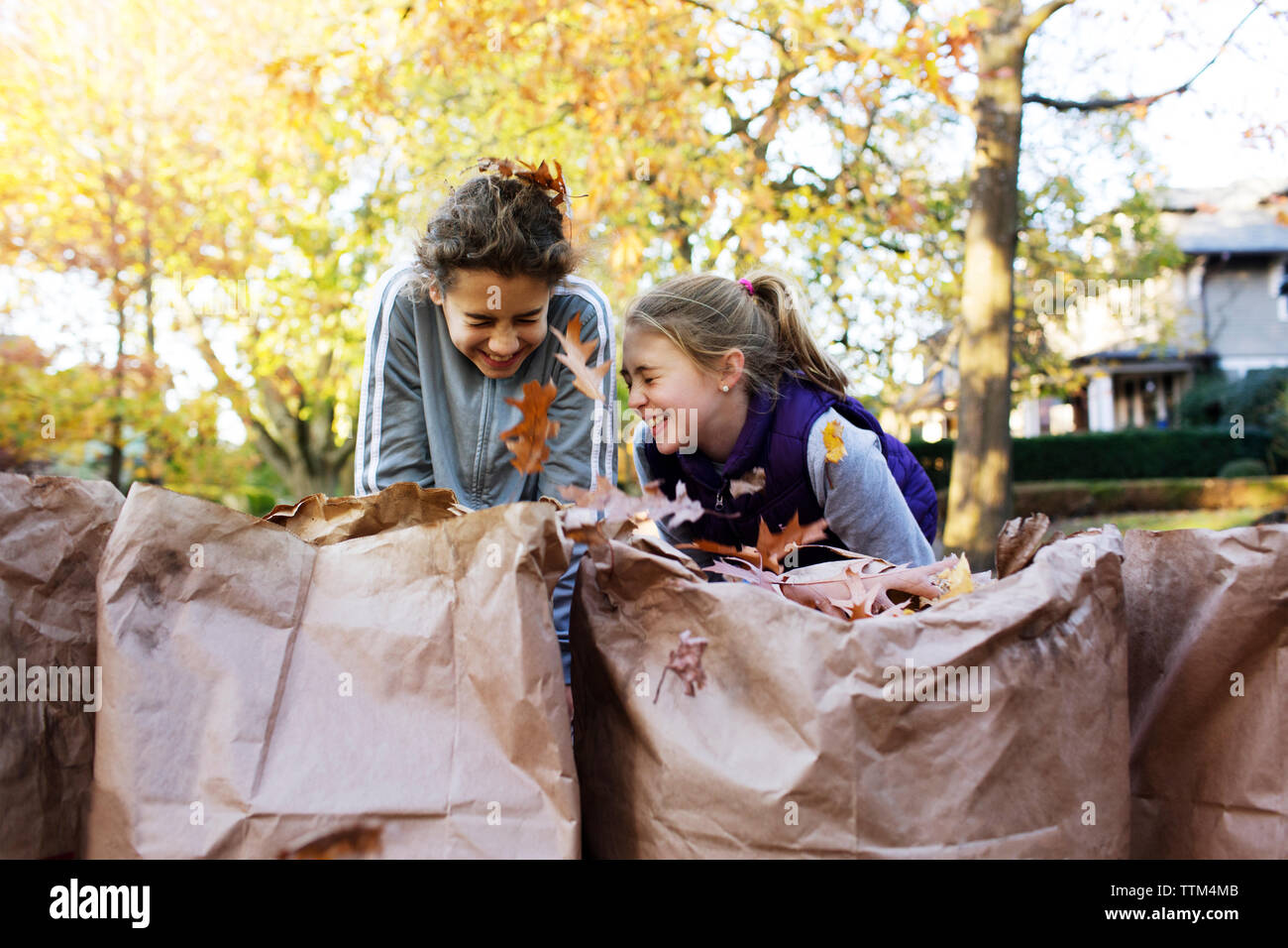 Happy amici ridere mentre la raccolta di foglie di autunno Foto Stock