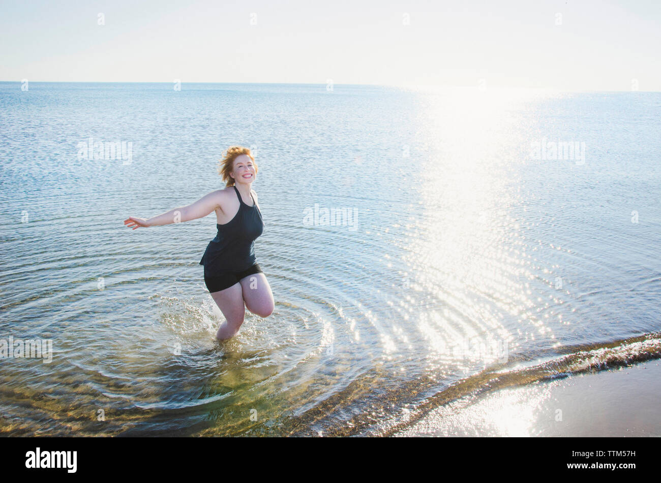 Elevato angolo di visione della donna spensierata in mare sulla riva contro il cielo chiaro Foto Stock Elevato angolo di visione della donna spensierata in mare sulla riva contro il cielo chiaro Foto Stock