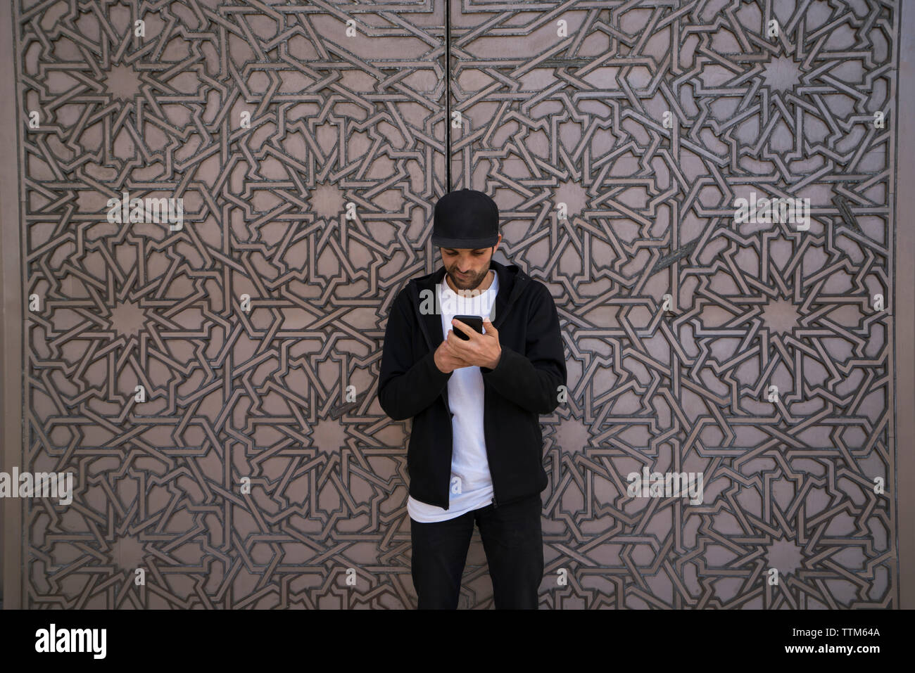Uomo che utilizza il cellulare mentre in piedi dalla porta Foto Stock