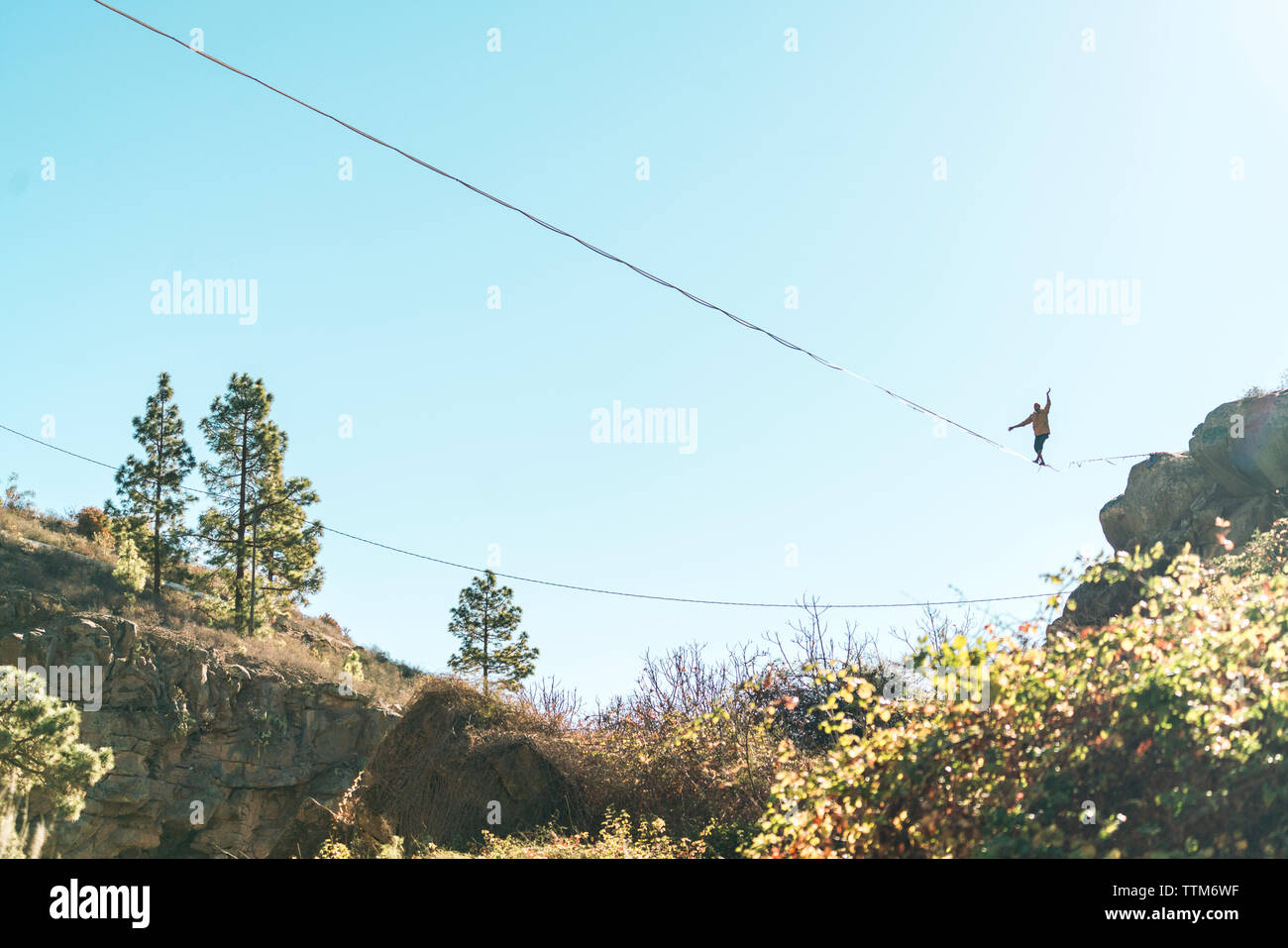 Basso angolo di visione dell'uomo slacklining contro il cielo chiaro durante la giornata di sole Foto Stock