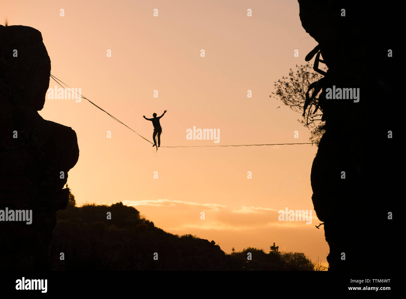Basso angolo vista di silhouette uomo slacklining contro sky durante il tramonto Foto Stock
