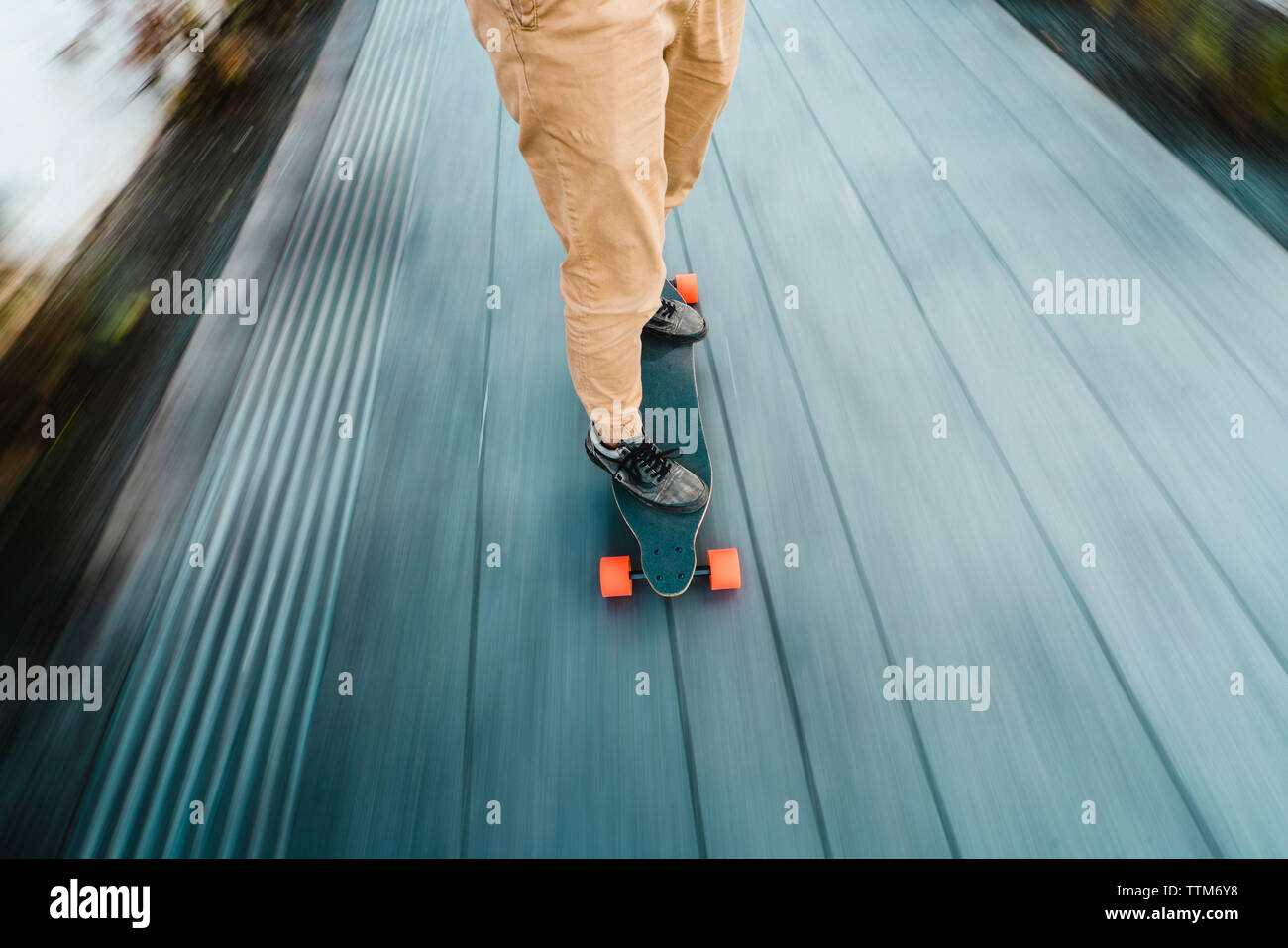 Sezione bassa dell'uomo lo skateboard su tavolato di legno in città Foto Stock