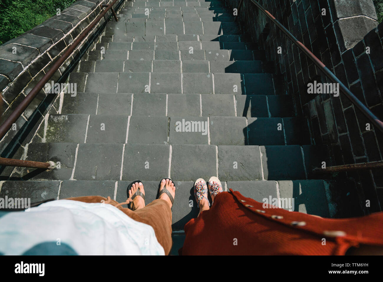 Sezione bassa di amici in piedi sui gradini durante la giornata di sole Foto Stock