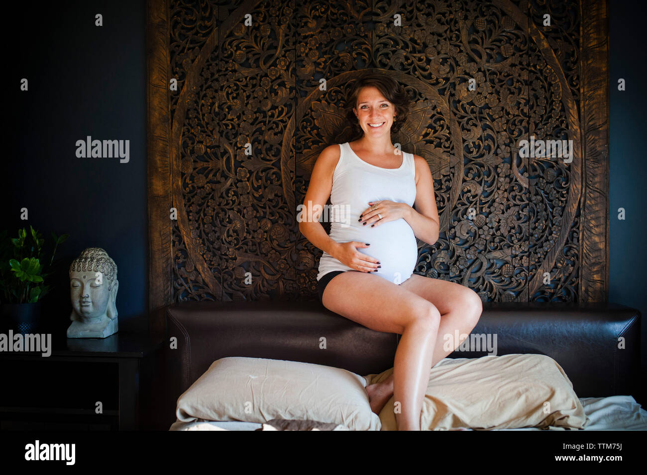 Ritratto di donna felice di toccare la pancia mentre è seduto sul resto della testa Foto Stock