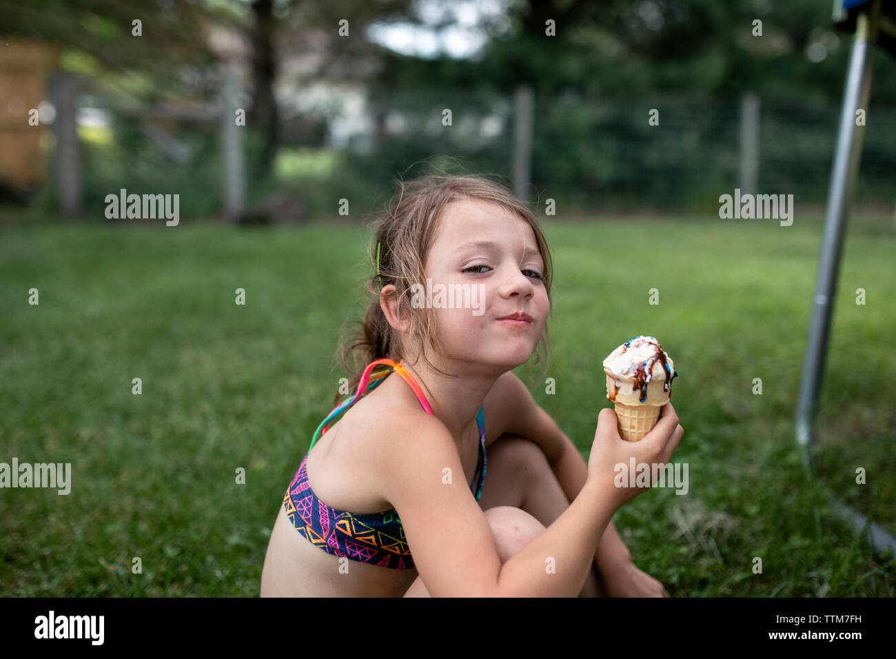 Ritratto di ragazza con cono gelato seduti in giardino Foto Stock