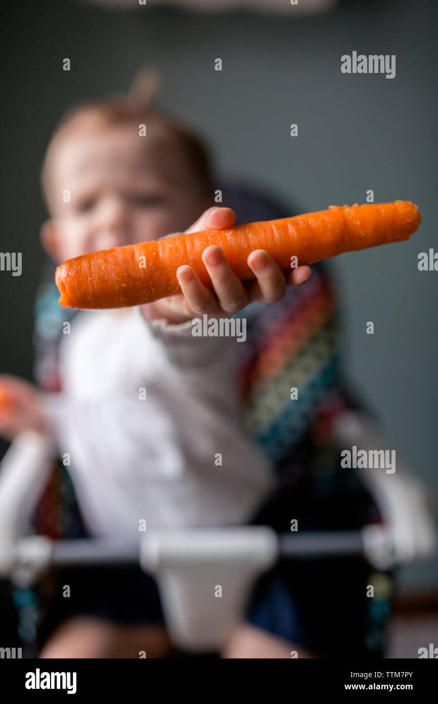 Baby girl tenendo la carota a casa Foto Stock