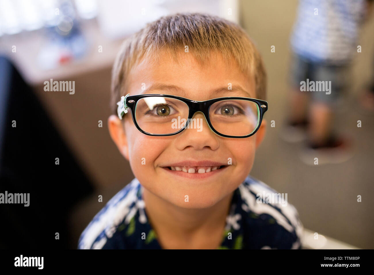 Età elementare ragazzo entusiasta di essere con gli occhiali in ufficio medici Foto Stock