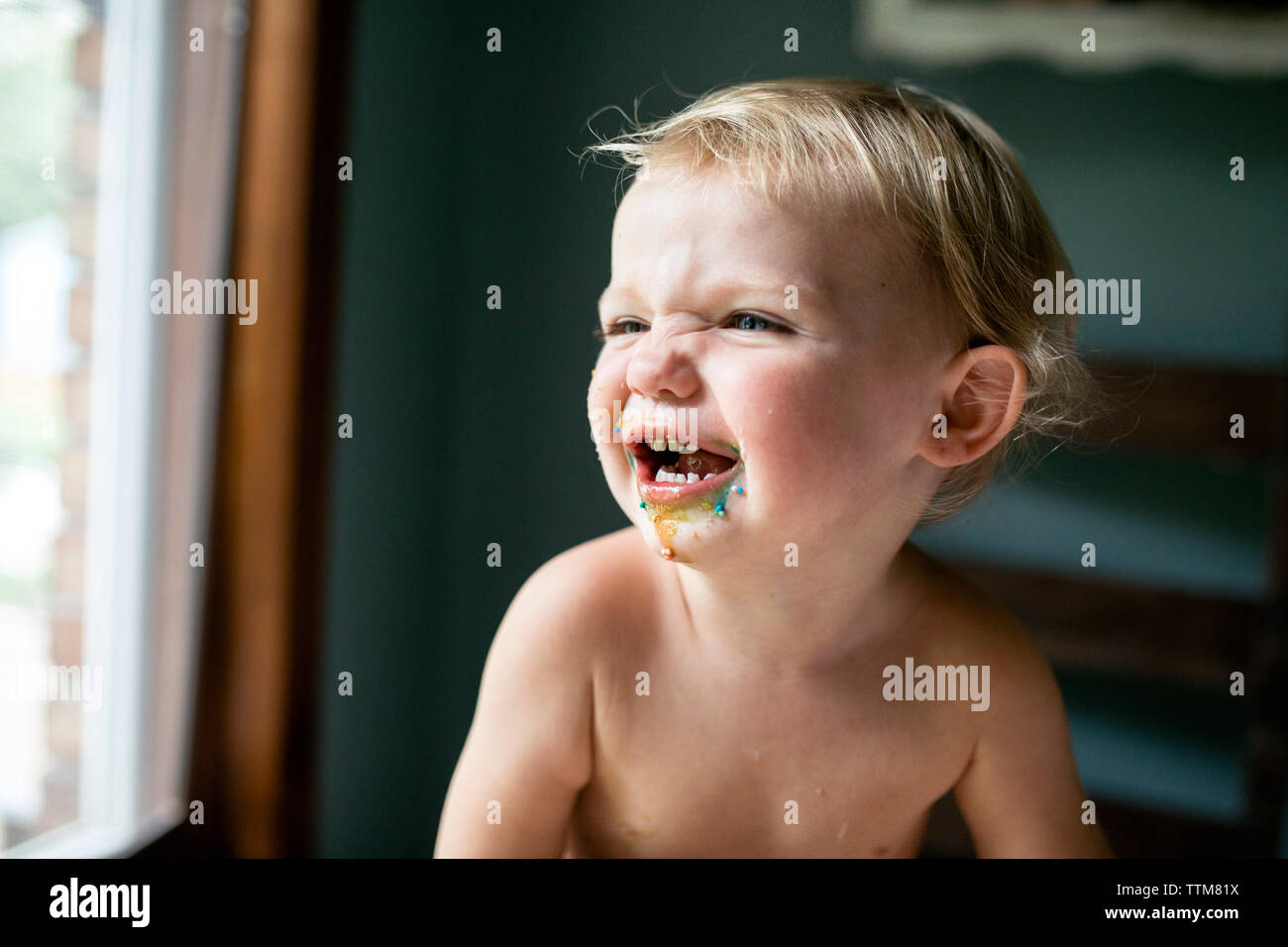 Il Toddler girl guardando lontano con faccia sporchi dopo aver mangiato trattare colorati Foto Stock