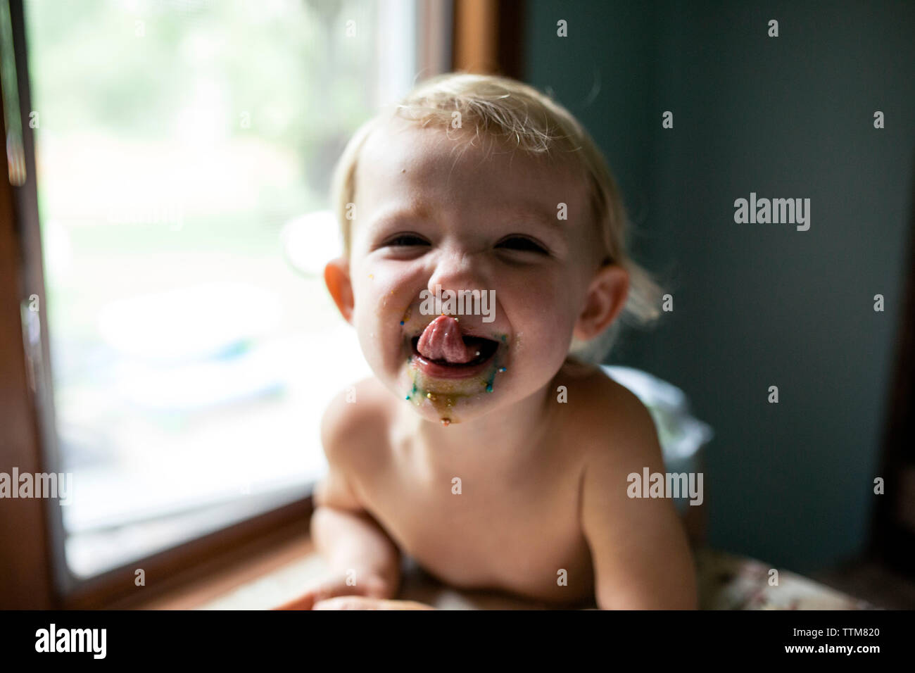 Il Toddler girl leccare spruzza fuori le labbra dopo aver mangiato il Dolcetto Foto Stock