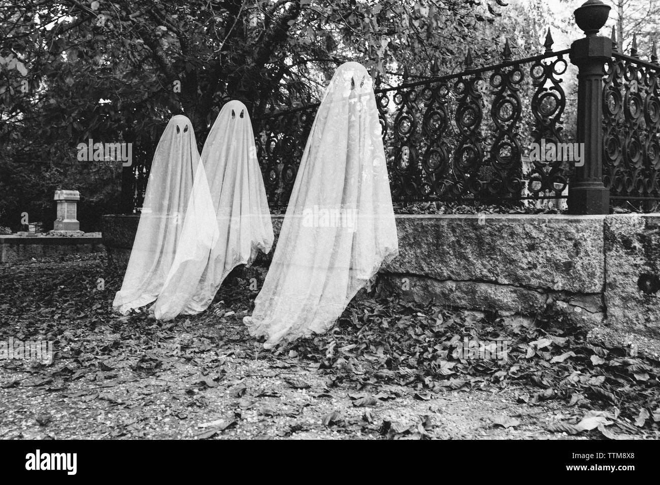 La doppia esposizione dei ragazzi in costumi fantasma al cimitero durante il periodo di Halloween Foto Stock