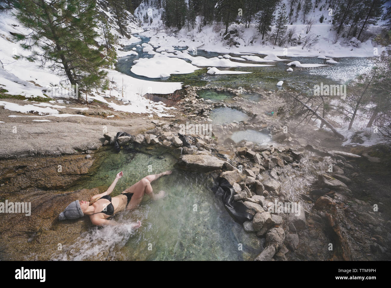 Elevato angolo di visione della donna che indossa un bikini mentre vi rilassate in piscina termale a forest durante il periodo invernale Foto Stock